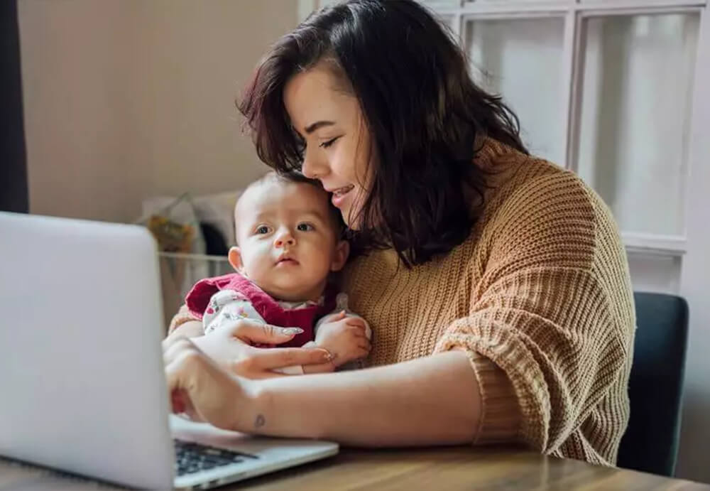 A multitasking mom holding her child, balancing work and family life