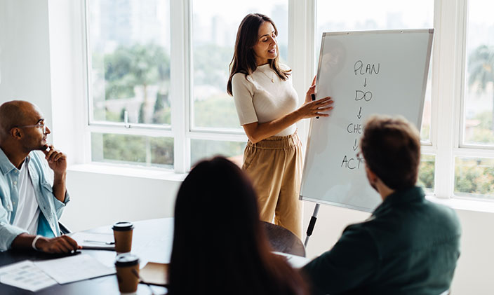Business woman standing in front of meeting room at a white board, going over plan