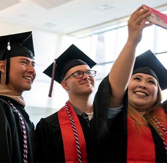 Three University of Phoenix graduates smile about exclusive tuition pricing for alumni