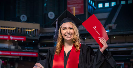graduate smiling and holding their diploma proudly