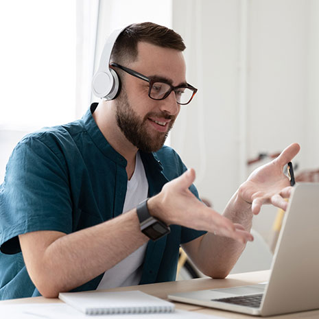 man with headphones speaking emphatically to computer