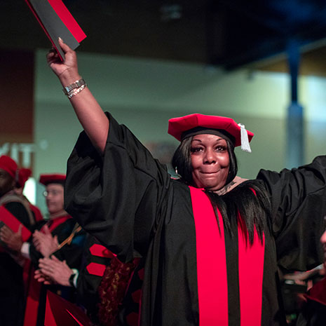 Graduating student holding their diploma and clapping
