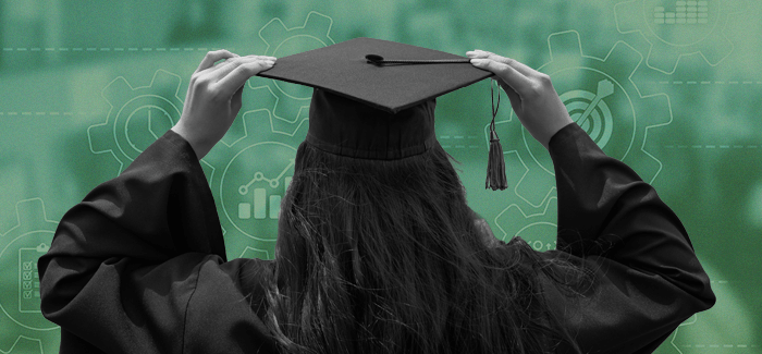 Female student in a graduation cap and gown looking at business trends and graphs to symbolize bachelor's degree in business