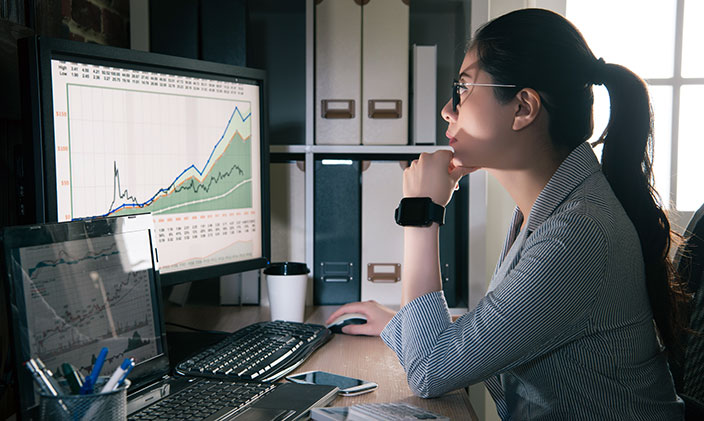 Young female information security analyst working on a computer showing a detailed chart