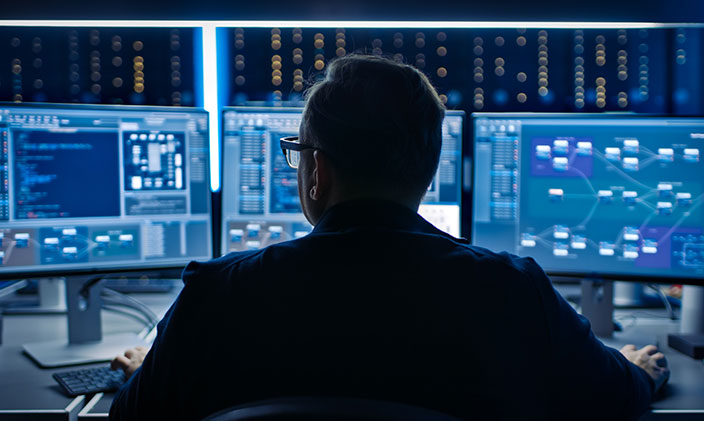 IT professional overlooking three computers