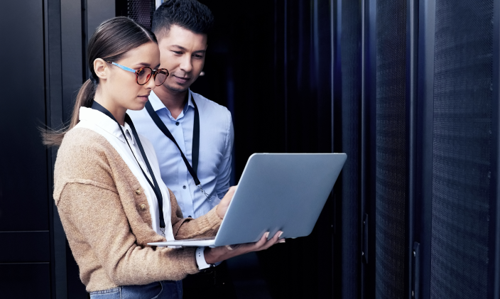 Two cybersecurity professionals discussing cryptography while looking at a laptop.
