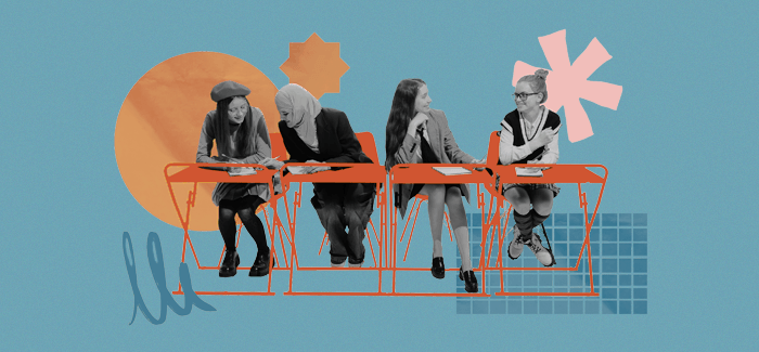 Four students sitting at desks and chatting in a welcoming classroom environment