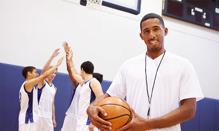 Male high school coach holding a basketball to signify a coaching career