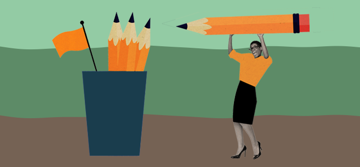 An aspiring teacher getting ready to take the Praxis test by lifting an oversize pencil to place in an oversize pencil cup