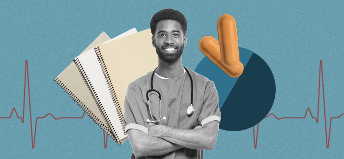 Male nurse in an entry-level healthcare job standing smiling with crossed arms and a stethoscope around his neck with notebooks, pills, and a heart rate chart in the background. 