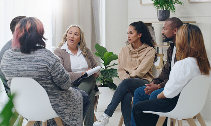A group of six diverse individuals sitting in a circle and talking about community health and public health
