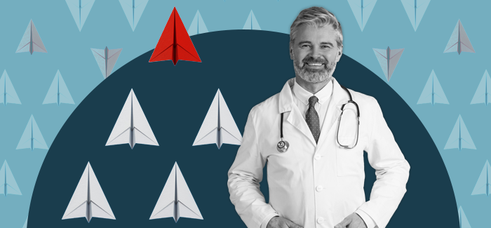A man in a healthcare leadership position  standing in front of a background filled with upwardly pointing paper airplanes.
