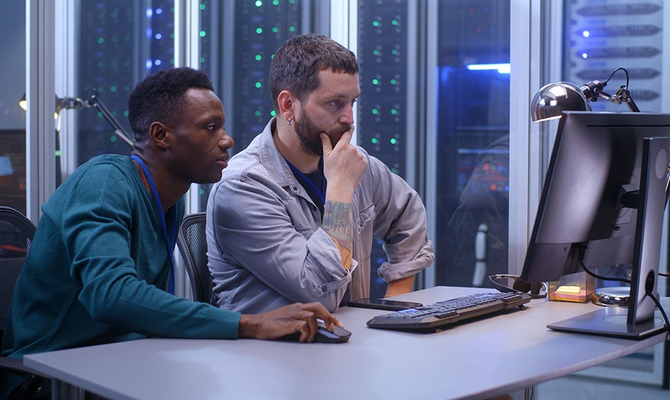 Two computer programmers work together in a server room