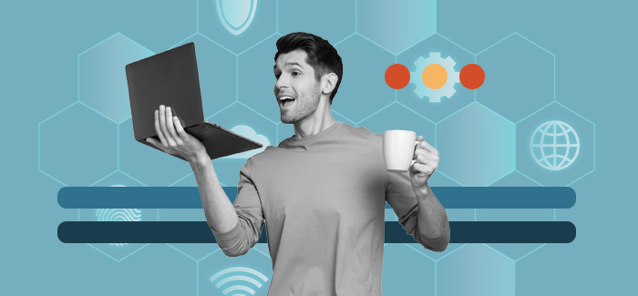 Male students working at a tech internship holding a laptop in one hand and a cup of coffee in the other.