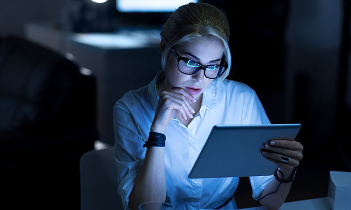 Female technician wearing glasses and looking at an ipad while learning about data modeling techniques