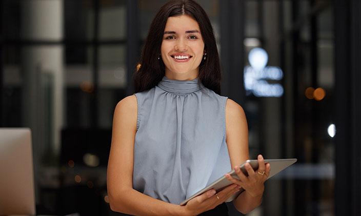 A marketing coordinator with a tablet computer smiling at the camera