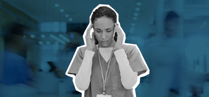 Nurse sitting with her hands in her hands together, looking worried and stressed like she could be suffering from nurse burnout.