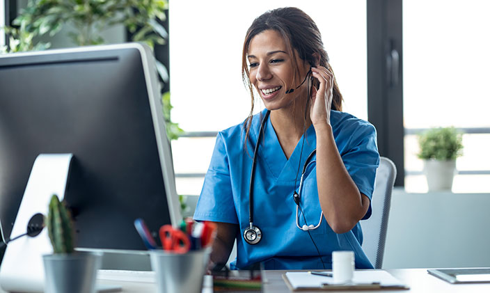 Female telehealth nurse on a call and smiling at her computer