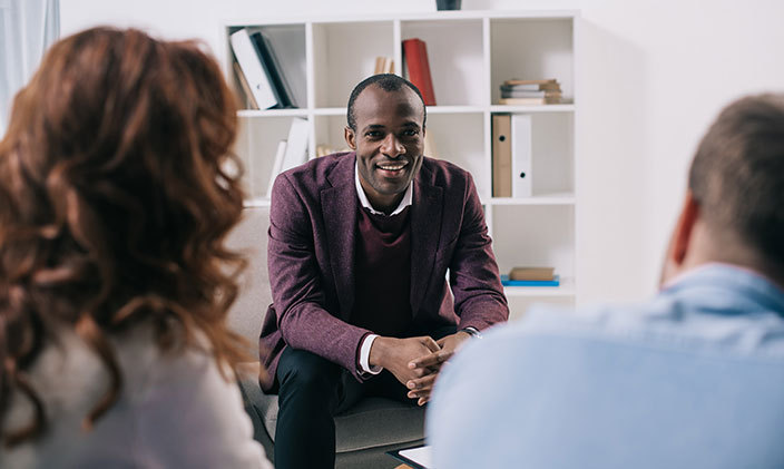 Man who has the skills for a social worker speaking to a couple in an office
