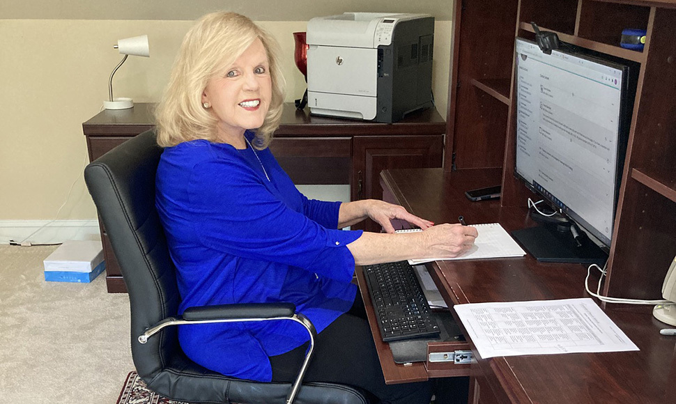 Donna Lange sitting at desk in home office and writing on notebook