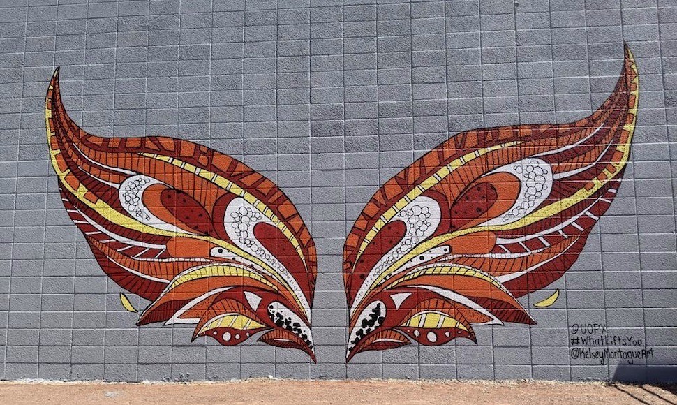 Mural of phoenix wings on the exterior wall of a UOPX building