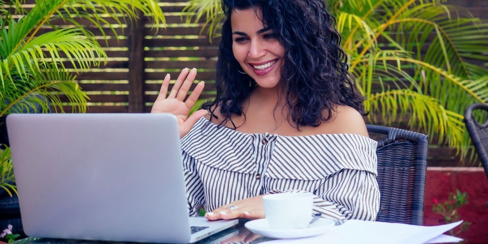 Woman waves into her laptop screen