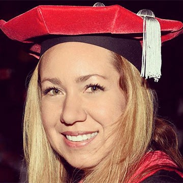 Picture of Giselle Poveda smiling and wearing a red graduation cap