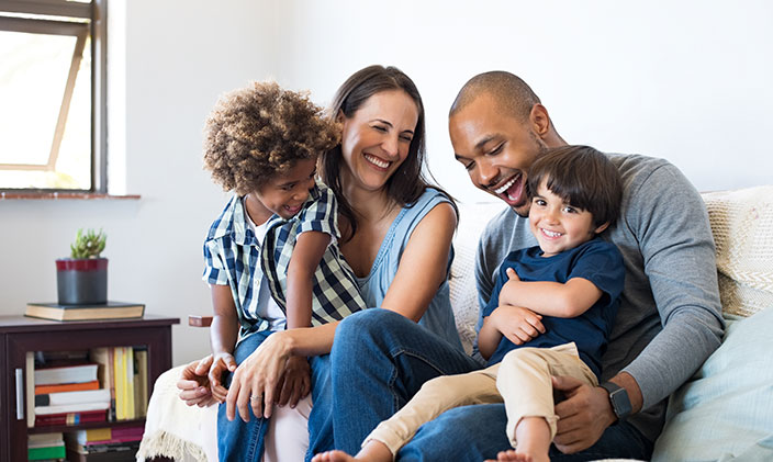 Happy family of four laughs on the couch together