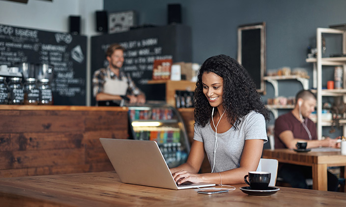 Woman smiling at laptop in a coffee shop