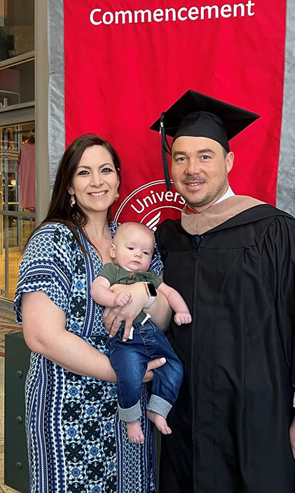 Jason Wells at commencement with his wife and son