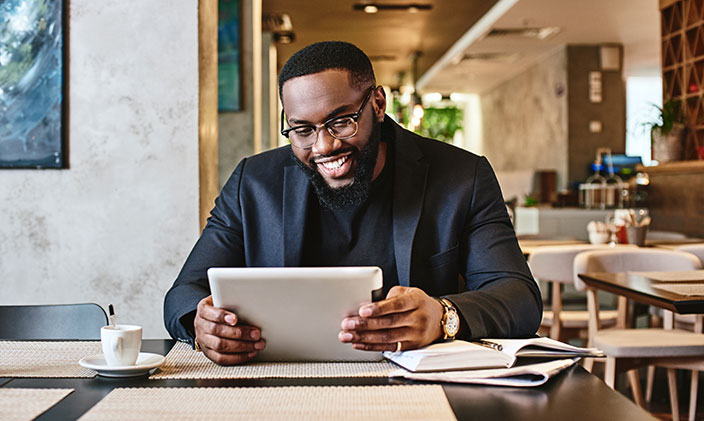 Businessman smiles while using a tablet in a restaurant