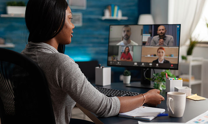 Female business professional working from home, on a call from her computer with four others on the screen