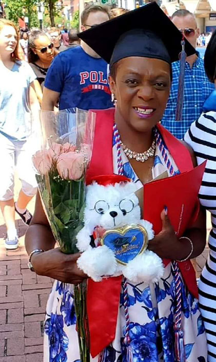 Barbara Smith at graduation in a sundress and cap with roses and a diploma
