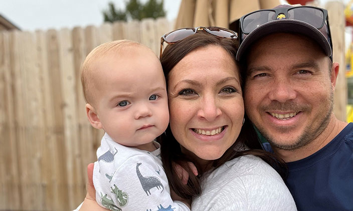 Jason Wells smiling with his lovely wife and baby son