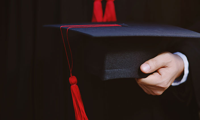 Male graduate holding a graduation cap to represent Marco Grijalva graduating from University of Phoenix.