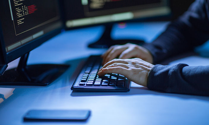 Photo of a pair of hands typing at a keyboard with a partial computer screen in view