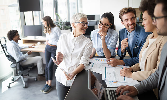 Professionals of different ages have a chat in a cool, gray workspace