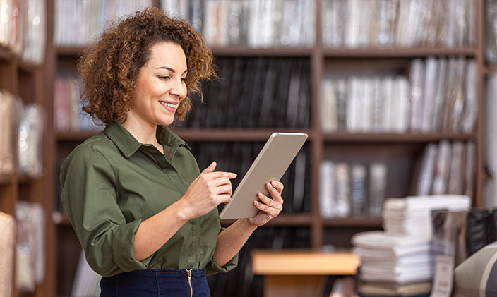 Hispanic female purchasing manager smiles at a tablet while standing in a records office