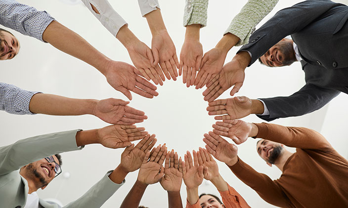 A diverse group of people putting their hands in the middle of a circle