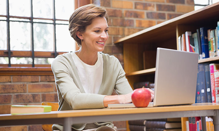Female teacher looking at laptop on her desk 