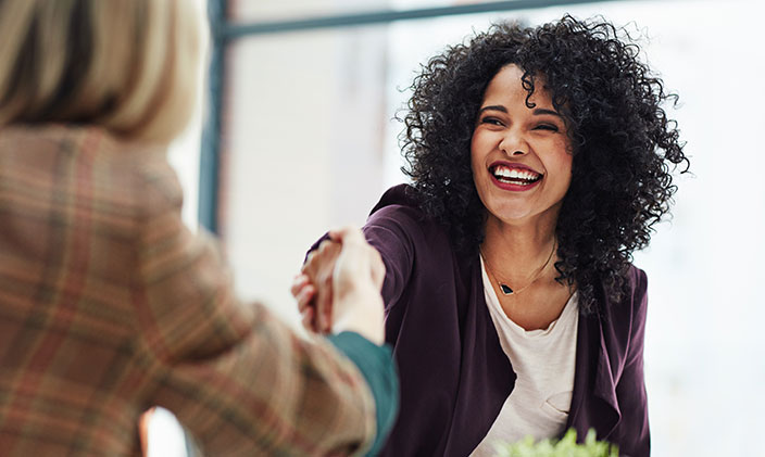 Woman shaking another's hand