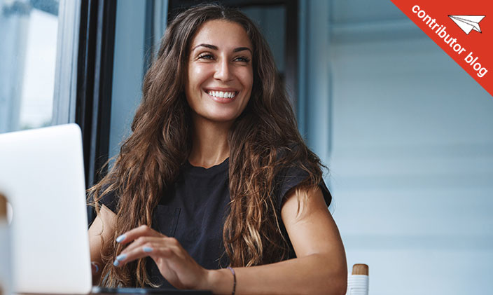 Woman smiling while working at laptop, image contains a tag identify this article as being by a contributor