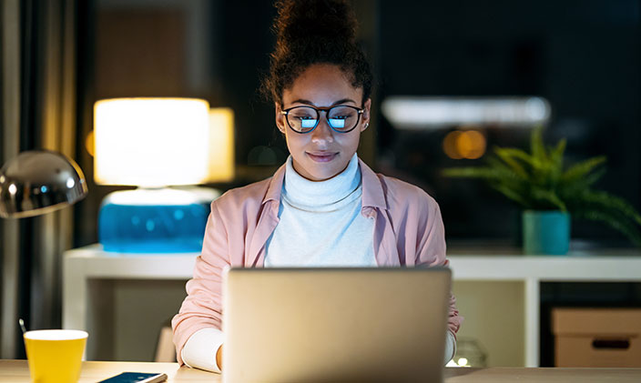 Woman in glasses working at her laptop at night