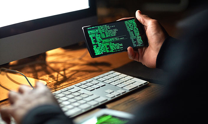 Hands are keyboard overlooking code on a phone screen
