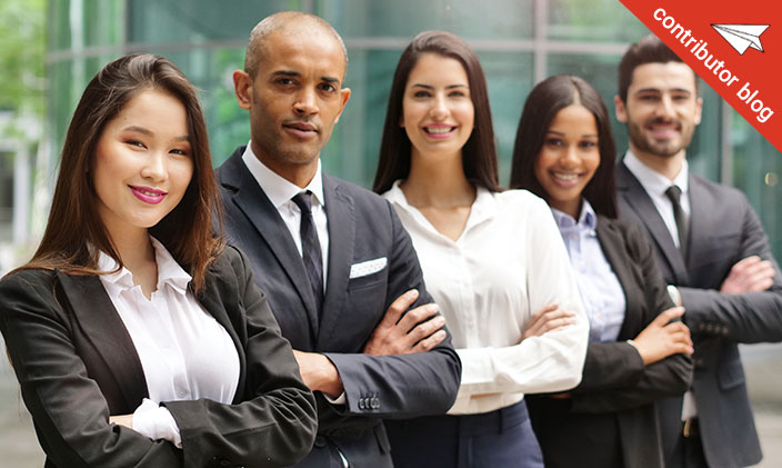 Group of professionals with diverse skill sets stand in professional attire with their arms crossed