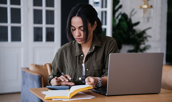 Student using calculator and a laptop to figure out a student loan repayment plan