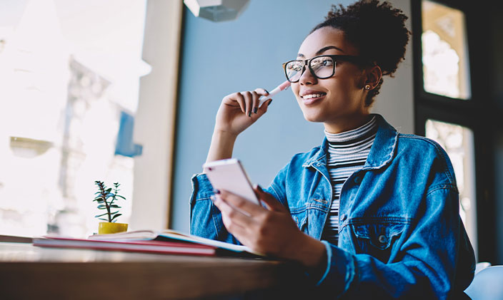 Woman smiling and thinking with phone in her hand