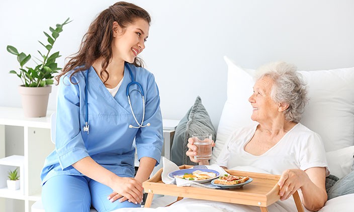 Certified nursing assistant feeding a senior patient