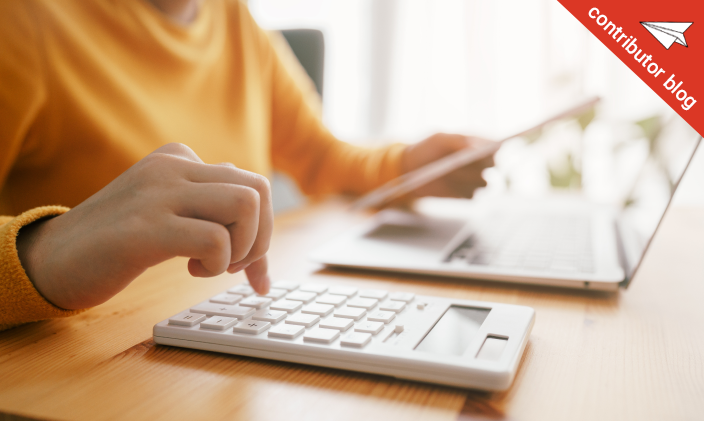 Zoomed in on a person using a calculator while looking at a laptop
