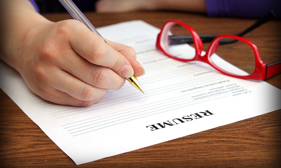 Person learning how to write a resume with red glasses nearby